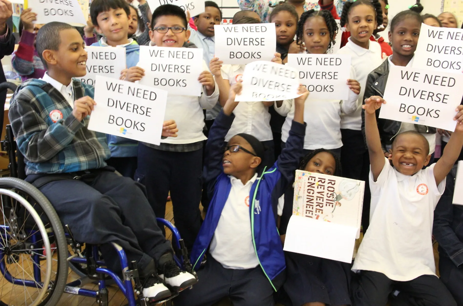 Photo of students holding up signs that read, We Need Diverse Books